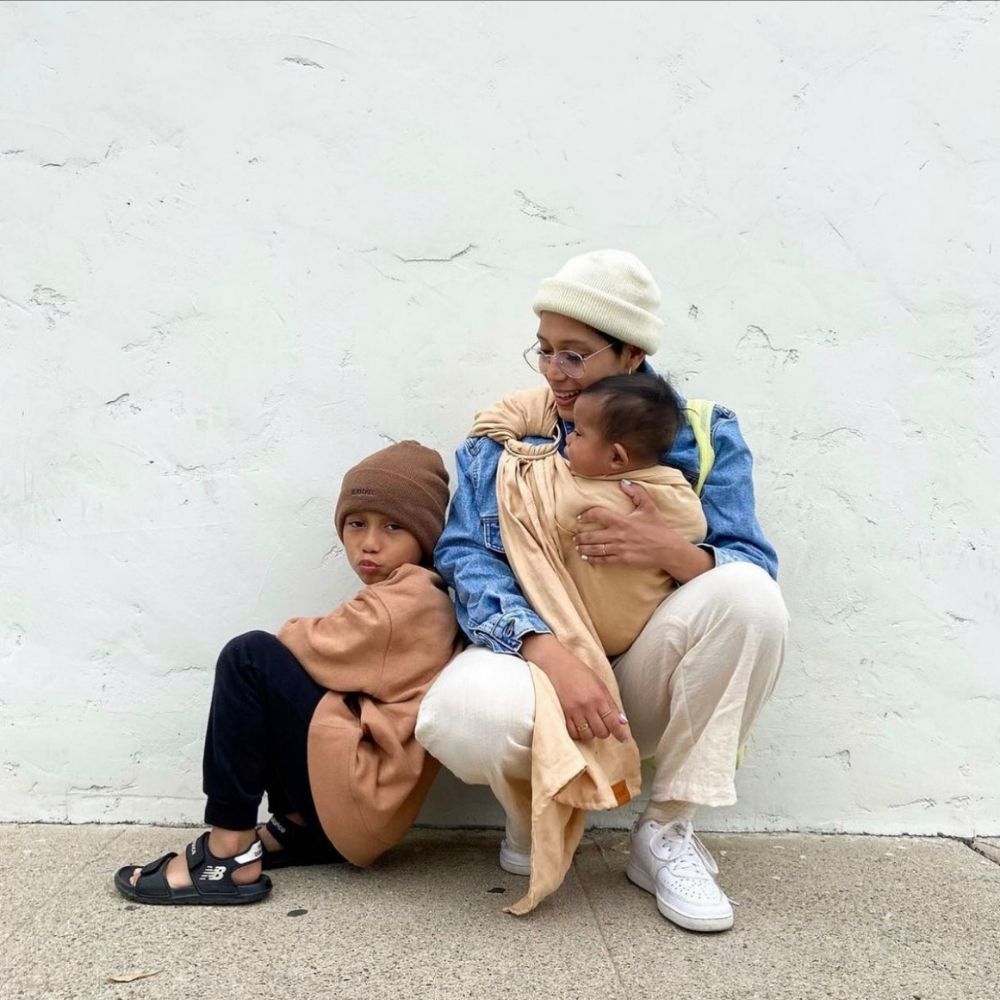 Anne, bebeğini halka sling ile taşırken büyük çocuğuyla birlikte günlük hayatını rahat ve konforlu şekilde sürdürüyor.