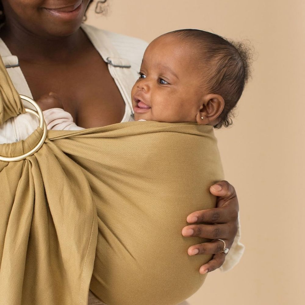 Halka sling içinde ergonomik pozisyonda taşınan bebeğin ve halka detayının yakın plan görünümü, bebeği güvenli ve konforlu taşımayı kolaylaştıran bebek taşıma slingini gösteriyor.